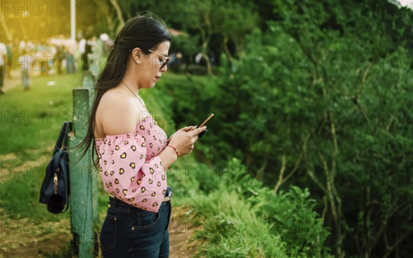 Latin woman checking her cell phone, pretty girl in glasses checking her cell phone