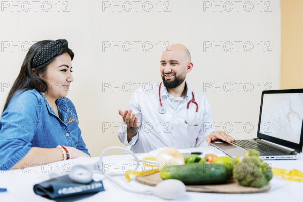 Smiling nutritionist explaining to a female patient, Nutritionist man talking to woman patient in office. Back view of a female patient talking to the nutritionist