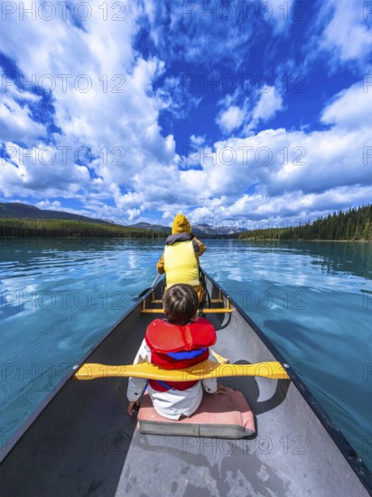 Tourists paddling a canoe on beautiful maligne lake in jasper national park, alberta, canada, enjoying a sunny day surrounded by stunning nature
