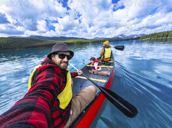Family enjoying a sunny day canoeing on maligne lake in jasper national park, alberta, canada, taking a selfie with beautiful mountain scenery in the background