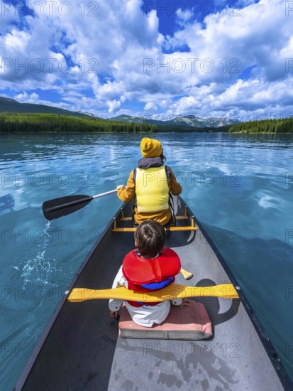 Father and son paddling a canoe on maligne lake's turquoise waters, surrounded by mountains and forests, enjoying summer vacation in jasper national park, alberta