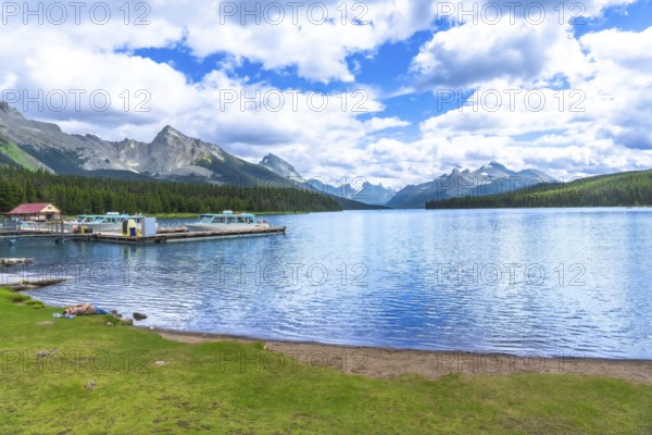 Tranquil maligne lake in jasper national park reflecting the majestic canadian rockies, with boats docked at spirit island, offers breathtaking views of pristine nature