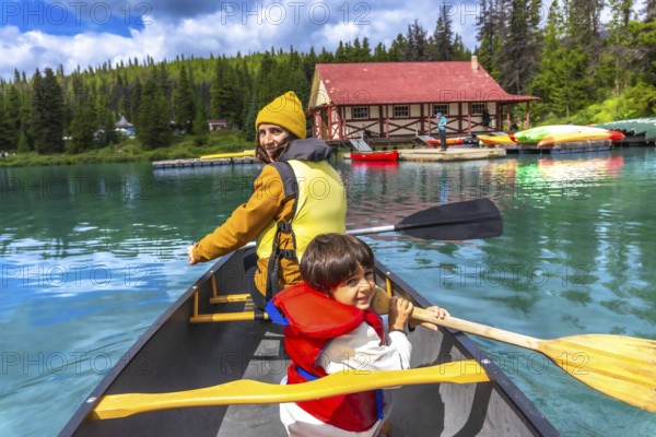 Mother and son are paddling a canoe on the beautiful turquoise maligne lake in jasper national park, enjoying a sunny summer day surrounded by nature