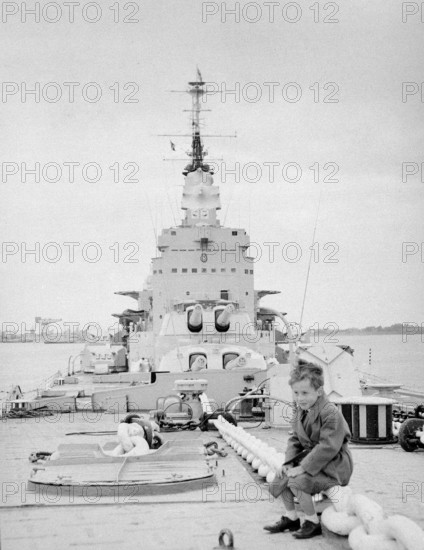 Boy sitting on deck of Royal Navy HMS Vanguard battleship, Devonport, Plymouth, Devon, England, UK c 1956