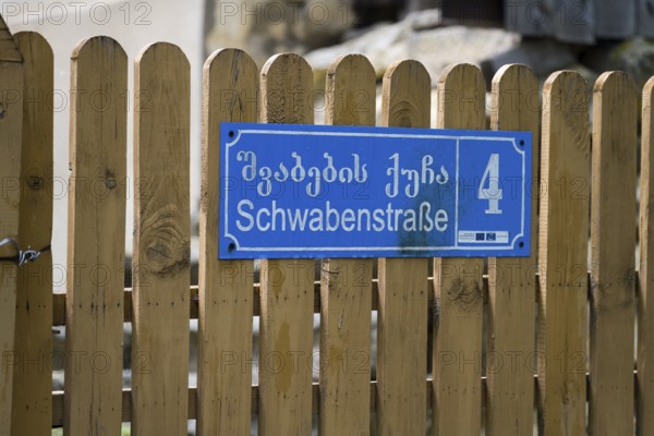 Blue street sign with house number 4 on a wooden fence in Georgian and German letters, Schwabenstraße, village founded by Caucasian Germans, Asureti, Asureti, Elizabeth Valley, Lower Kartli region, Georgia