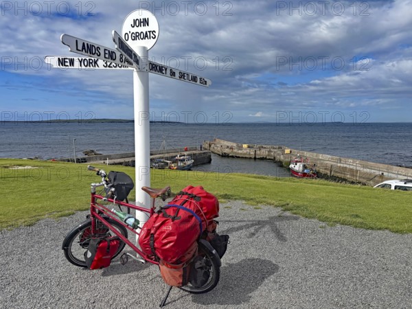 Packed bike in front of lake sign and harbor view in John O'Groats, bicycle trips, bicycle adventures, Scotland, Great Britain