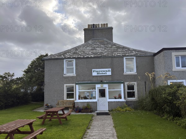 Classic hotel view under cloudy sky with green surroundings and picnic tables, only hotel on Westray Island, Orkney Islands, Scotland, Great Britain