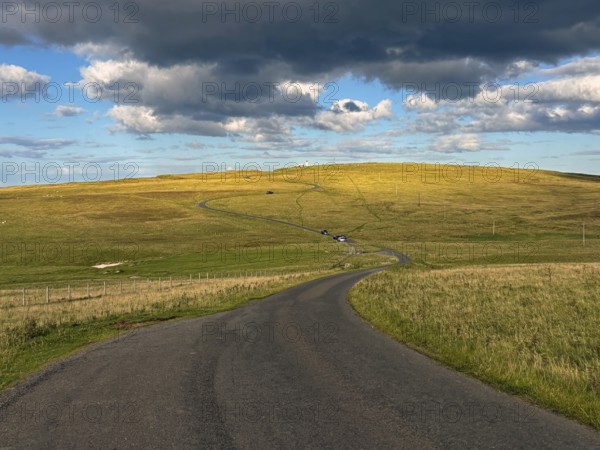 Road running through rolling fields under cloudy sky at dusk, Duncansby Stacks, John O' Groats Scotland, United Kingdom