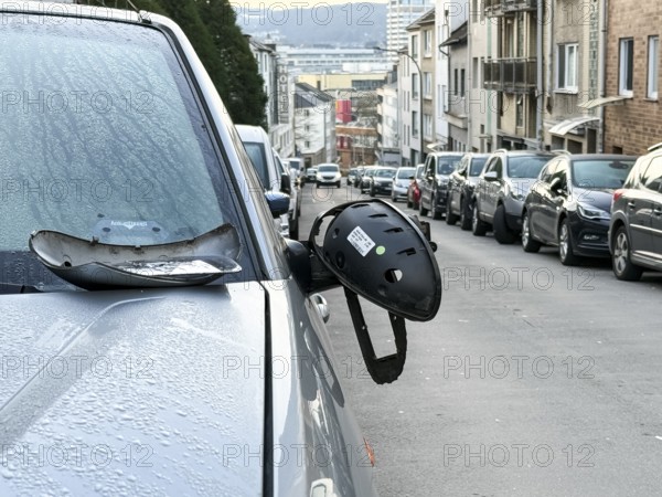 A car on the side of a steep residential street. The vehicle's left wing mirror is severely damaged and part of the mirror is on the hood, Wuppertal, Germany