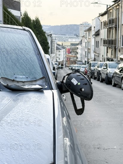 A car on the side of a steep residential street. The vehicle's left wing mirror is severely damaged and part of the mirror is on the hood, Wuppertal, Germany
