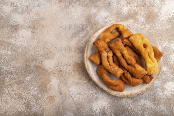 Crunchy biscuit Brushwood cookies sprinkled with powdered sugar on brown concrete background, top view, flat lay, copy space