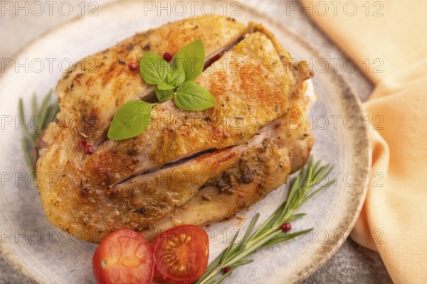 Fried Turkey Thigh with spices and rosemary on plate on brown concrete background and orange linen textile. side view, close up, selective focus