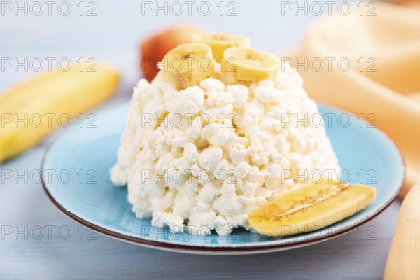 White ?ottage cheese, Curd, with Banana on blue wooden background and orange textile, side view, close up, selective focus
