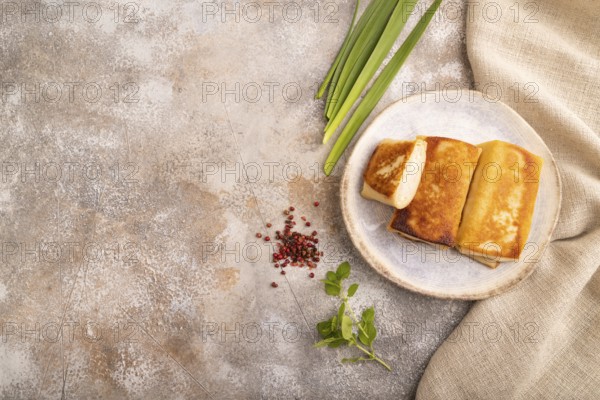 Fried crispy pancakes with meat and cheese on brown concrete background and linen textile. top view, flat lay, copy space