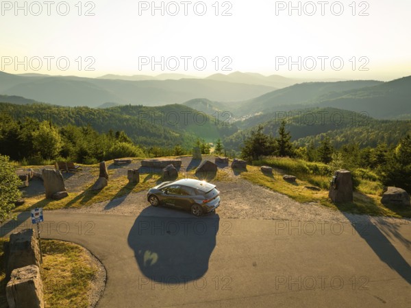 Car parked at a viewing point with a wide view over a mountainous forest area at sunset, deer e-car sharing, Cupra electric car, Bad Wildbad, Germany