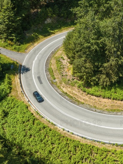 Car on a winding road in the forest, taken from a bird's eye view, Deer E-car sharing, Cupra electric car, Germany