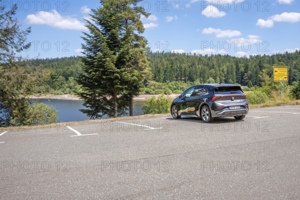 Car in a parking lot overlooking a lake and surrounded by a green forest, deer e-car sharing, Cupra electric car, Germany