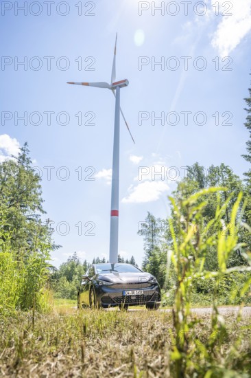 Car standing under a large wind turbine in sunny weather in a field, Deer E-Car Sharing, Cupra electric car, Germany