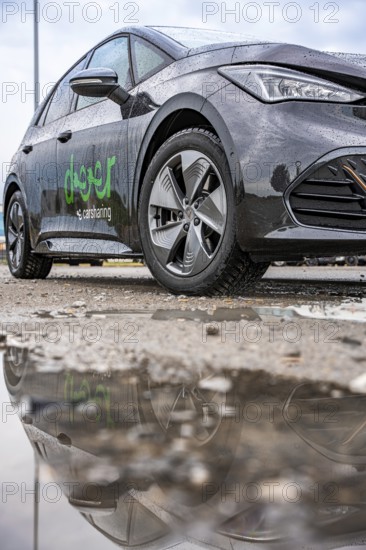 Car with reflection in a wet puddle on a street, Deer E-Car Sharing, Cupra electric car, Germany