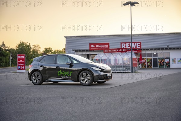 Car parked in a parking lot in front of a supermarket in the evening light, Deer e-car sharing, Cupra electric car, Germany