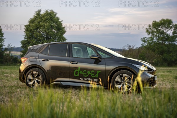 Black car seen from the side in a meadow with evening light, Deer e-car sharing, Cupra electric car, Germany