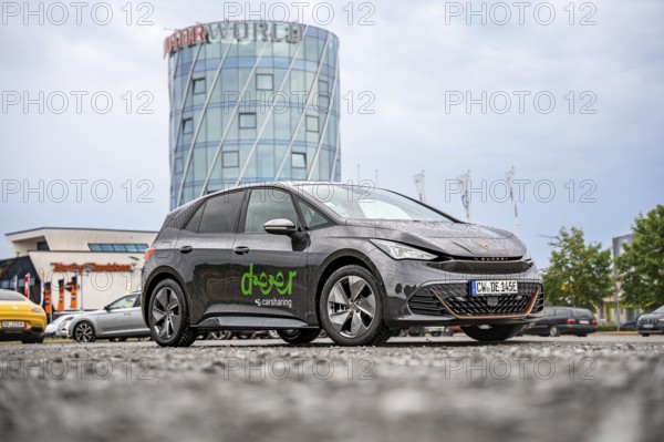 Car next to a modern tower and shopping center, deer e-car sharing, Cupra electric car, Motorworld. Böblingen, Germany