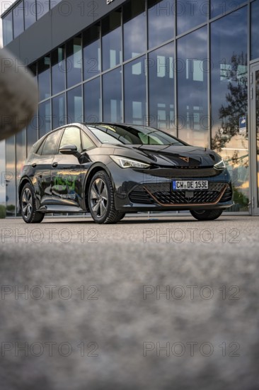 Black car in front of a modern building with glass façade, photographed on concrete floor, Deer E-Car Sharing, Cupra electric car, Böblingen, Germany