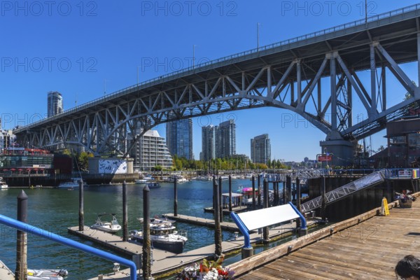 Granville street bridge dominating the skyline over false creek with boats moored at the marina and modern buildings in the background, vancouver, british columbia, canada