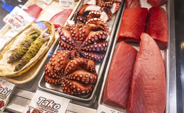 Fresh octopus and tuna fillets are displayed on ice alongside wasabi at a fish market in vancouver, british columbia, canada, offering a vibrant display of seafood delicacies