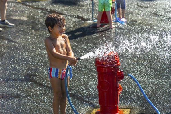 Happy child spraying water from a fire hydrant during a hot summer day in vancouver, british columbia, enjoying a playful moment of refreshment and fun