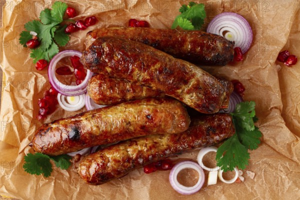 Fried kupaty on parchment, with red onion and pomegranate, kupaty, Georgian cuisine