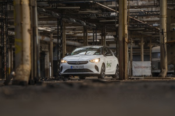 A white car with car sharing logo is parked in an old industrial building, Deer E-Car Sharing, Motorworld Rüsselsheim, Germany