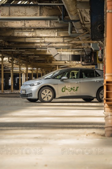A car with the car sharing logo is parked in a light-flooded industrial building, Deer E-Car Sharing, Motorworld Rüsselsheim, Germany