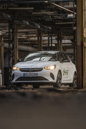 A white Opel with car sharing logo drives through an urban, industrial environment, Deer E-Car Sharing, Motorworld Rüsselsheim, Germany