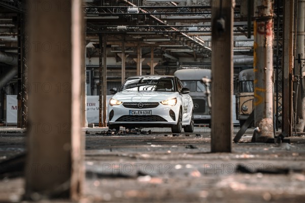 A car is parked in an empty, structured factory building, accentuated by light and shadow, Deer E-Car Sharing, Motorworld Rüsselsheim, Germany