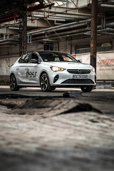 A small car against an industrial backdrop with structured elements and rugged charm, Deer E-Car Sharing, Motorworld Rüsselsheim, Germany