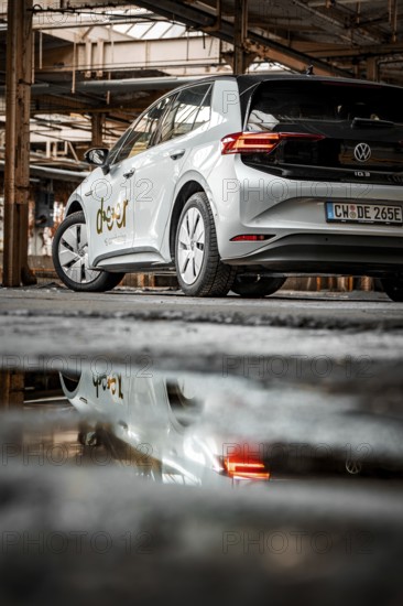 The vehicle is reflected in a puddle on the floor of an abandoned factory, Deer E-Car Sharing, Motorworld Rüsselsheim, Germany