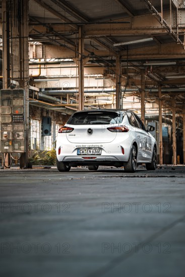 White vehicle in a large, empty industrial building, urban feel, Deer E-Car Sharing, Motorworld Rüsselsheim, Germany