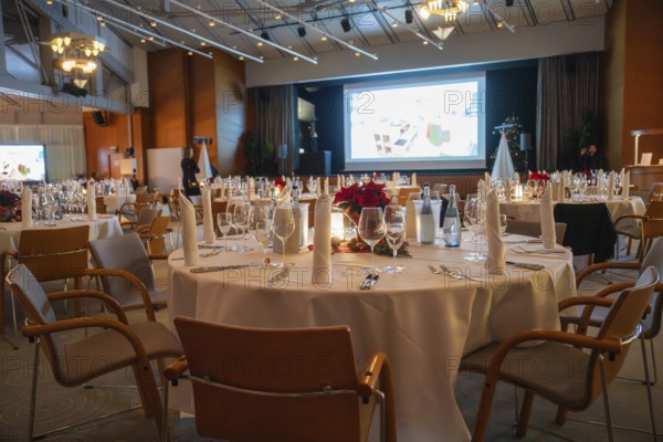 A tastefully furnished room with set tables and a large screen, Christmas party Dekra Congresshotel Wart, Calw district, Germany