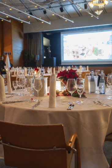 An elegant banquet hall with festively decorated tables and a projection screen in the background, Dekra Congresshotel Wart Christmas party, Calw district, Germany