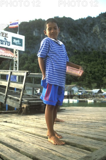 Young boy in the stilt village of Ko Pannyi in Phangnga Bay near Ko Phuket selling souvenirs to tourists, two years in front of the tsunami, Thailand, December 2002, vintage, retro, old, historic
