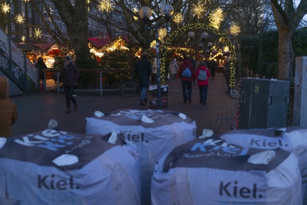 Safety measures for the Christmas market on Holstenplatz in Kiel, city center, Christian festival, lettering, barrier, sandbags, barriers, protection, fear, danger, evening, glowing stars, booths, trees, pedestrian zone, Christmas decorations, visitors, Schleswig-Holstein, Germany