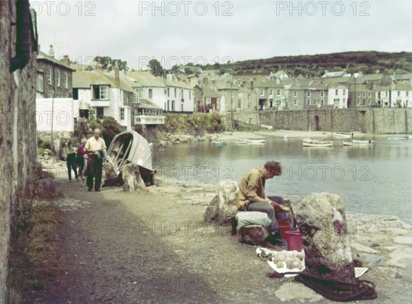 People on coastal path at seaside village of Mousehole, Cornwall, England, UK c 1960
