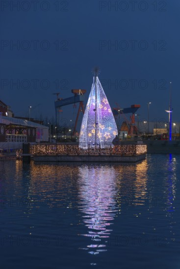 Christmas decoration in Kiel at the boat harbor, festive lighting, glow of lights, evening, darkness, island of lights, shipyard on the fjord, Christmas tree with stars, water reflection, Schleswig-Holstein, Germany
