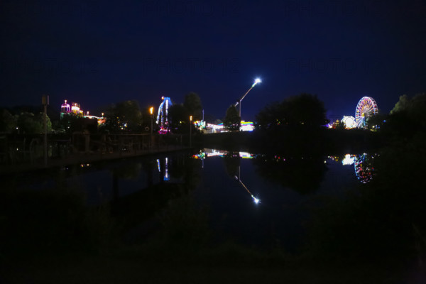 Fairground in Ulm Friedrichsau at night, folk festival, hustle and bustle, fair, Ferris wheel, amusement park, amusement attraction, ride, artificial light, darkness, reflection in natural lake, Ausee, Ferris wheel, Ulm, Baden-Württemberg, Germany