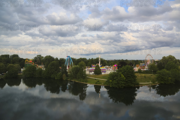Fairground in Ulm Friedrichsau, folk festival, hustle and bustle, Ferris wheel, amusement park, amusement attraction, ride, gray clouds, reflection in the natural lake, Ausee, Ferris wheel, Ulm, Baden-Württemberg, Germany