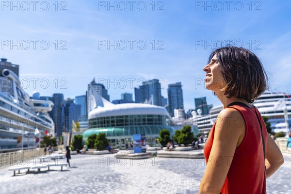 Happy tourist admiring the stunning vancouver downtown skyline, featuring cruise ships docked at canada place on a bright, sunny summer day in beautiful british columbia