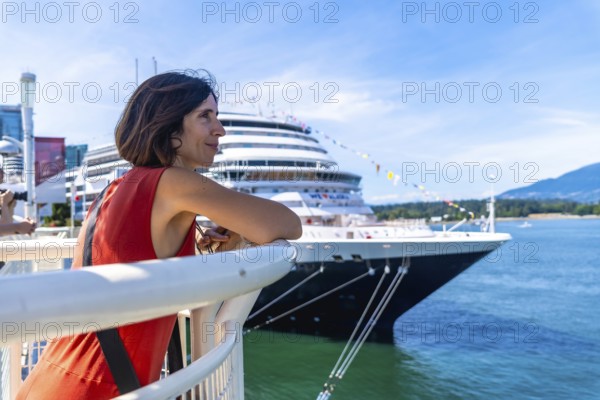 Tourist leaning on railing, admiring large cruise ship docked in harbor of vancouver, british columbia, canada, enjoying sunny day and anticipating upcoming voyage