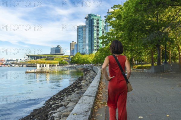 Tourist walking through a park along the waterfront in vancouver, british columbia, soaking in the vibrant cityscape under the warm sun on a beautiful summer day