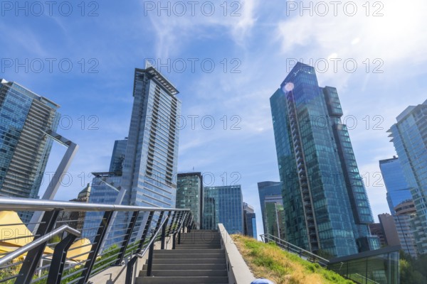 Modern skyscrapers dominate the skyline of vancouver, british columbia, seen from a low angle perspective emphasizing their height and contemporary design against a vibrant blue sky